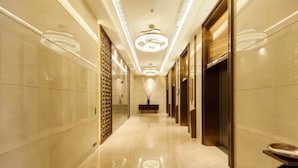 A long, well-lit hallway with a central chandelier, flanked by mirrored walls and doors leading to rooms. - Jinyi Jinglan Hotel (Jinhua)