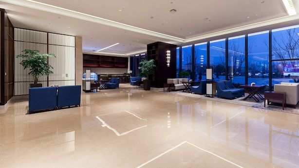 A modern lobby with a polished floor, seating areas, and large windows offering views of the cityscape. - Jinyi Jinglan Hotel (Jinhua)