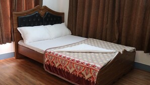A bed with a wooden headboard, a white mattress, and a patterned bedspread. - Great Nepal Bed & Breakfast (Lalitpur)