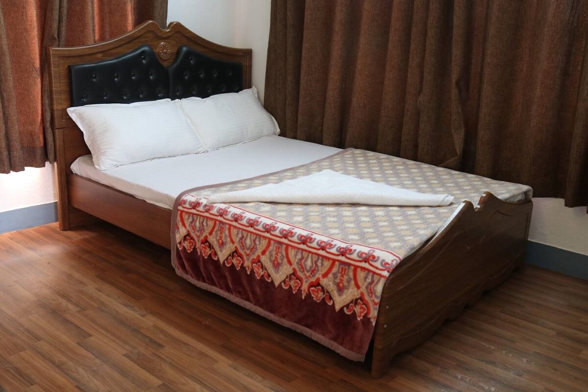 A bed with a wooden headboard, a white mattress, and a patterned bedspread.