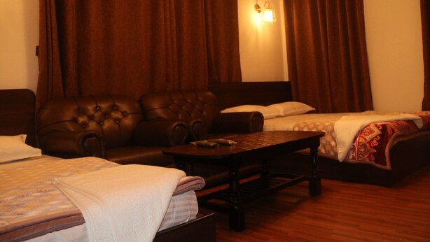 A hotel room with a large bed, a smaller bed, a sofa, and a wooden table. - Great Nepal Bed & Breakfast (Lalitpur)