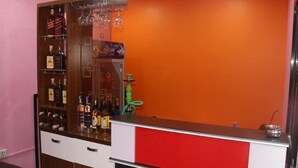 A bar area with shelves of liquor bottles, a red counter, and a green hookah. - Great Nepal Bed & Breakfast (Lalitpur)