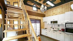 A wooden interior with a staircase, kitchen area, and a chandelier. - Beach Terrace Pension Taean (Taean)