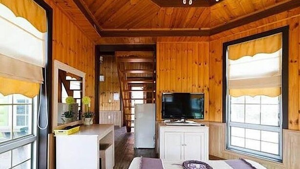 A wooden interior with a television, cabinets, and large windows. - Beach Terrace Pension Taean (Taean)