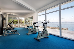 A gym with cardio machines and a view of a body of water.