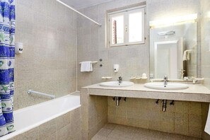 Ein Badezimmer mit zwei Waschbecken, einer Badewanne, einer Dusche und einem Fenster.