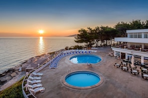 A pool area with two pools, lounge chairs, and outdoor seating.