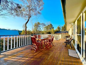 A wooden deck with a table and chairs, a bench, and a railing.