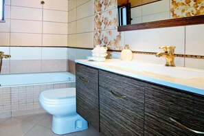 Ein Badezimmer mit einer Badewanne, Toilette und Waschtisch mit Spiegel.