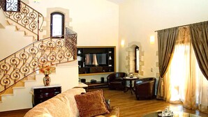 A living room with a staircase, a sofa, a coffee table, and a television. - Cretan Villa Near Beach for 10 (Kondomari)