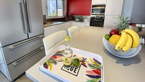 A modern kitchen with stainless steel appliances, a red accent wall, and a fruit bowl on the counter. - Villa SEA VIEW, 5' from Grand Case Beach, private pool, huge privacy (saint martin)