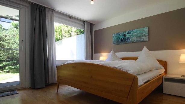 Un dormitorio con una cama de madera, vistas a la vegetación exterior y un cuadro en la pared.