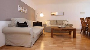 Una sala de estar con dos sofás, una mesa de centro y una zona de comedor con sillas.