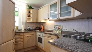 Una cocina con armarios de madera clara, encimera de granito, horno empotrado y pileta de acero inoxidable.