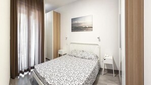 A bedroom with a bed, a bedside table, a chair, a wall-mounted telephone, and a picture on the wall. - Apartment in Pietra Ligure with garden (Pietra Ligure)