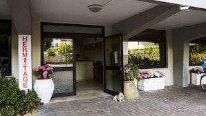 A hotel entrance with a sign reading "HERMITAGE," a glass door, and potted plants. - Apartment in Pietra Ligure with garden (Pietra Ligure)