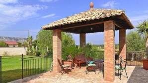 A covered patio area with a tiled roof, brick pillars, and outdoor furniture.