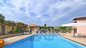 A swimming pool with lounge chairs and a pergola.
