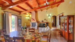 A cozy dining area with a wooden ceiling, a table with a colorful tablecloth, and a cabinet with glass doors.