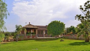 A house with a tiled roof, a covered porch, and a well-maintained lawn.