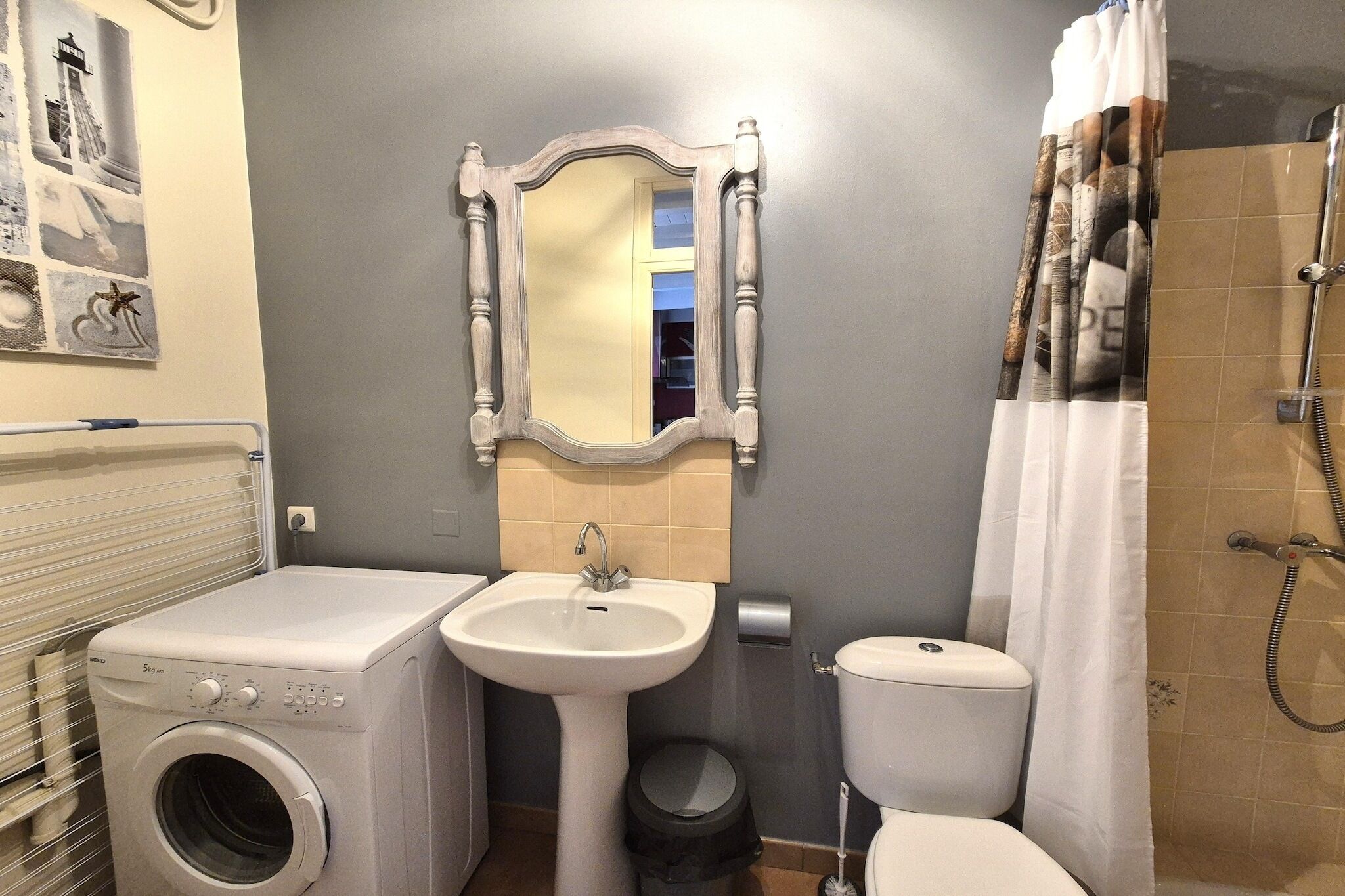 A compact bathroom with a washing machine, sink, toilet, and shower.