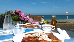 Een tafel met een maaltijd, een glas bier en uitzicht op het strand.