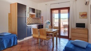 A compact living space with a kitchenette, a dining area, and a small seating area. - Seaside Apartment in Gallura (Santa Teresa Gallura (SS))