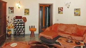 A living room with a sofa, a coffee table, a wine rack, and artwork on the walls. - Holiday Home Floridia with Pool near Beach (Siracusa)