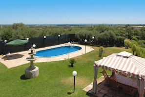 Ein Garten mit Swimmingpool, einer Pergola und einem Essbereich.