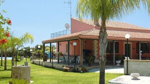 A house with a tiled roof, a covered patio, and a well-maintained lawn. - Holiday Home Floridia with Pool near Beach (Siracusa)