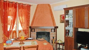 A dining area with a fireplace, wooden cabinets, and a television. - Holiday Home Floridia with Pool near Beach (Siracusa)