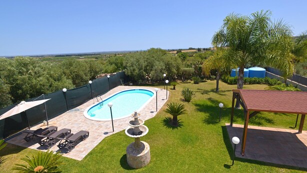 A backyard with a swimming pool, lounge chairs, a pergola, and a decorative fountain. - Holiday Home Floridia with Pool near Beach (Siracusa)