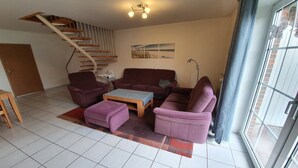 Ein Wohnzimmer mit Treppe, einer Sofagarnitur, einem Couchtisch und einer Stehlampe.