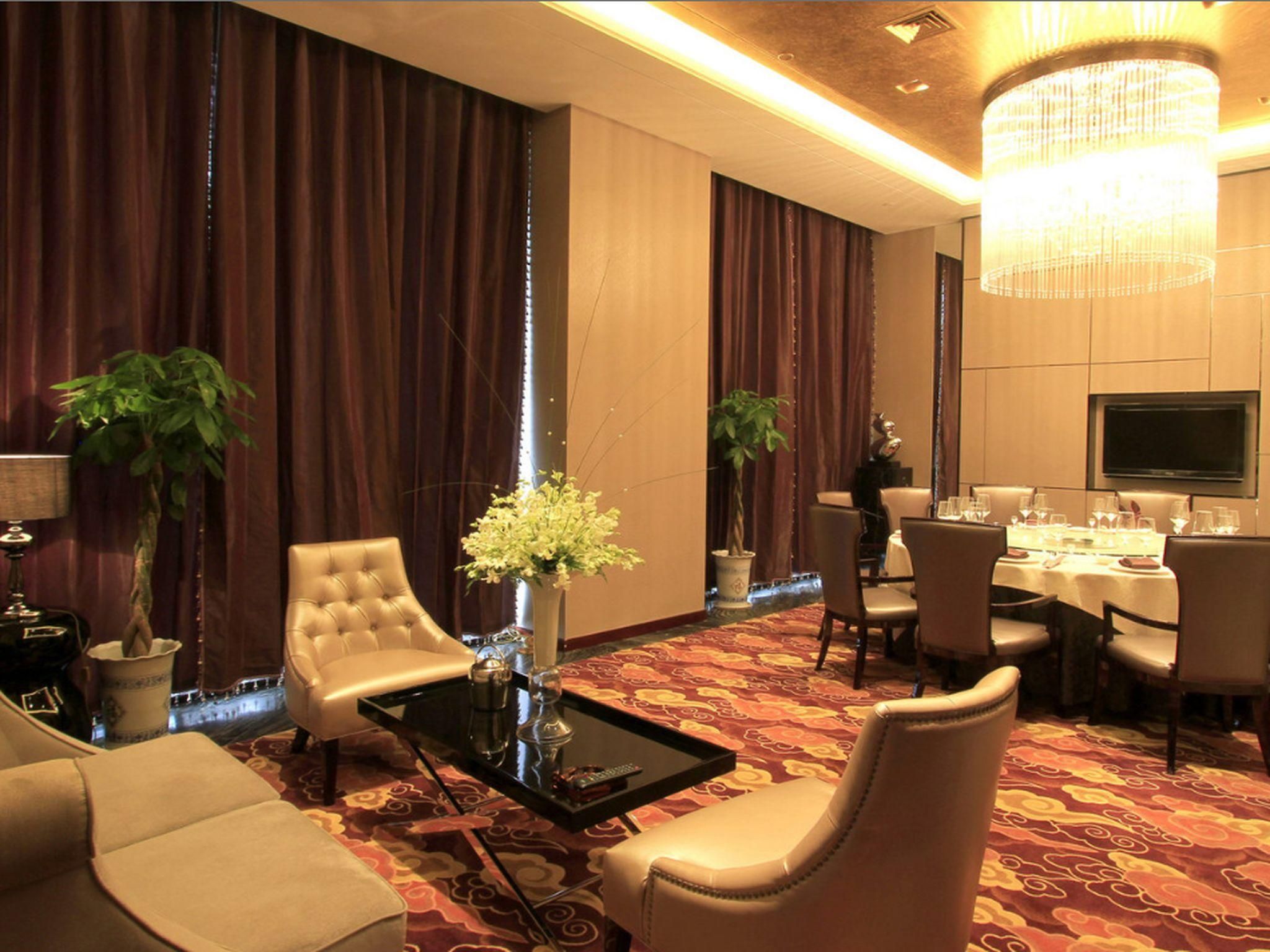 A hotel room with a seating area, a dining table, and a television.