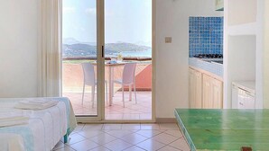 Quarto de hotel com varanda, mesa de jantar e área de cozinha.