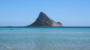 Visão nítida de uma ilha montanhosa com águas calmas em primeiro plano.