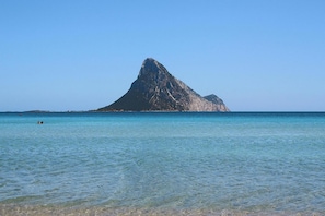 Visão nítida de uma ilha montanhosa com águas calmas em primeiro plano.