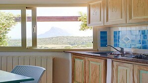 Uma cozinha com armários de madeira, uma janela com vista para uma montanha e um painel de azulejos.