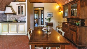 A kitchen with a brick ceiling, white cabinets, a wooden dining table, and a view into another room. - Country House in Tuscany with Pool and Tennis (Santo Pietro Belvedere)