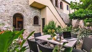 An outdoor dining area with a stone building, a staircase, and lush greenery. - Country House in Tuscany with Pool and Tennis (Santo Pietro Belvedere)