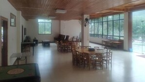 A spacious room with wooden ceiling and large windows, furnished with multiple wooden tables and chairs. - Natural Lodge Homestay (Guilin)