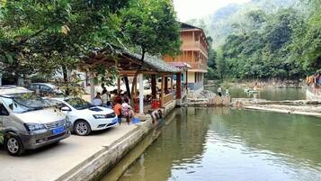 A riverside building with a covered porch, a dock, and a calm river.