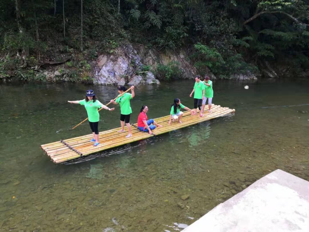 A group of people on a bamboo raft in a river surrounded by greenery.