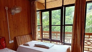 A room with two beds, a wooden ceiling, and large windows with a view of greenery. - Natural Lodge Homestay (Guilin)