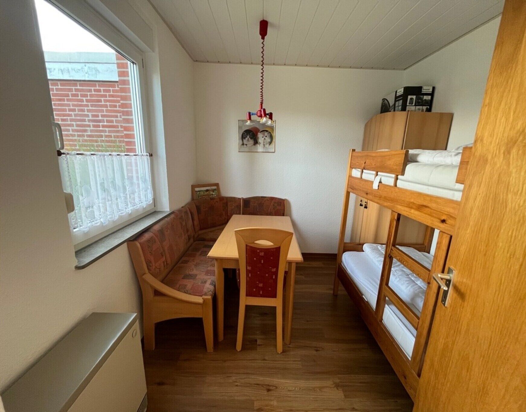 A compact room with a bunk bed, a wooden table, and a bench.