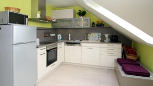 A compact kitchen with a refrigerator, oven, microwave, and a coffee maker. - Appartementhaus am Kiessee, Westerholt (Westerholt)