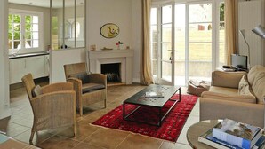 Un salon spacieux doté d’une cheminée, d’un coin repas et d’une grande porte-fenêtre coulissante donnant sur un jardin.