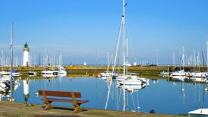 Un port de plaisance où sont amarrés de nombreux bateaux, un phare et un banc.