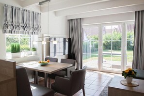 A modern kitchen with a dining area, large windows, and a view of the garden.