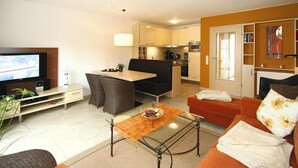 A compact living space with a television, seating area, kitchenette, and a dining table.